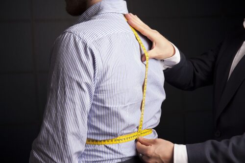 A tailor taking a body measurement with a tape measure